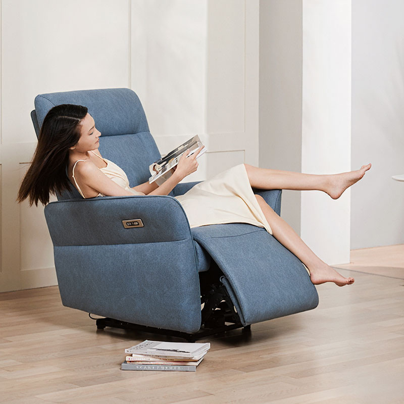 fauteuil massant Serenity bleu dans un salon avec femme assise