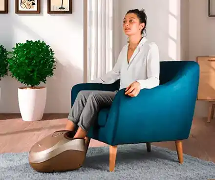Femme assise se faisant masser les pieds et mollets avec un masseur pieds Footbox