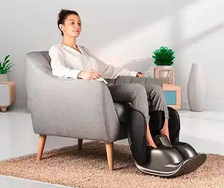 Femme assise se faisant masser les pieds et mollets avec un masseur pieds